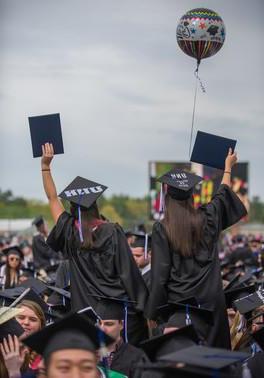 students holding up diplomas at Commencement